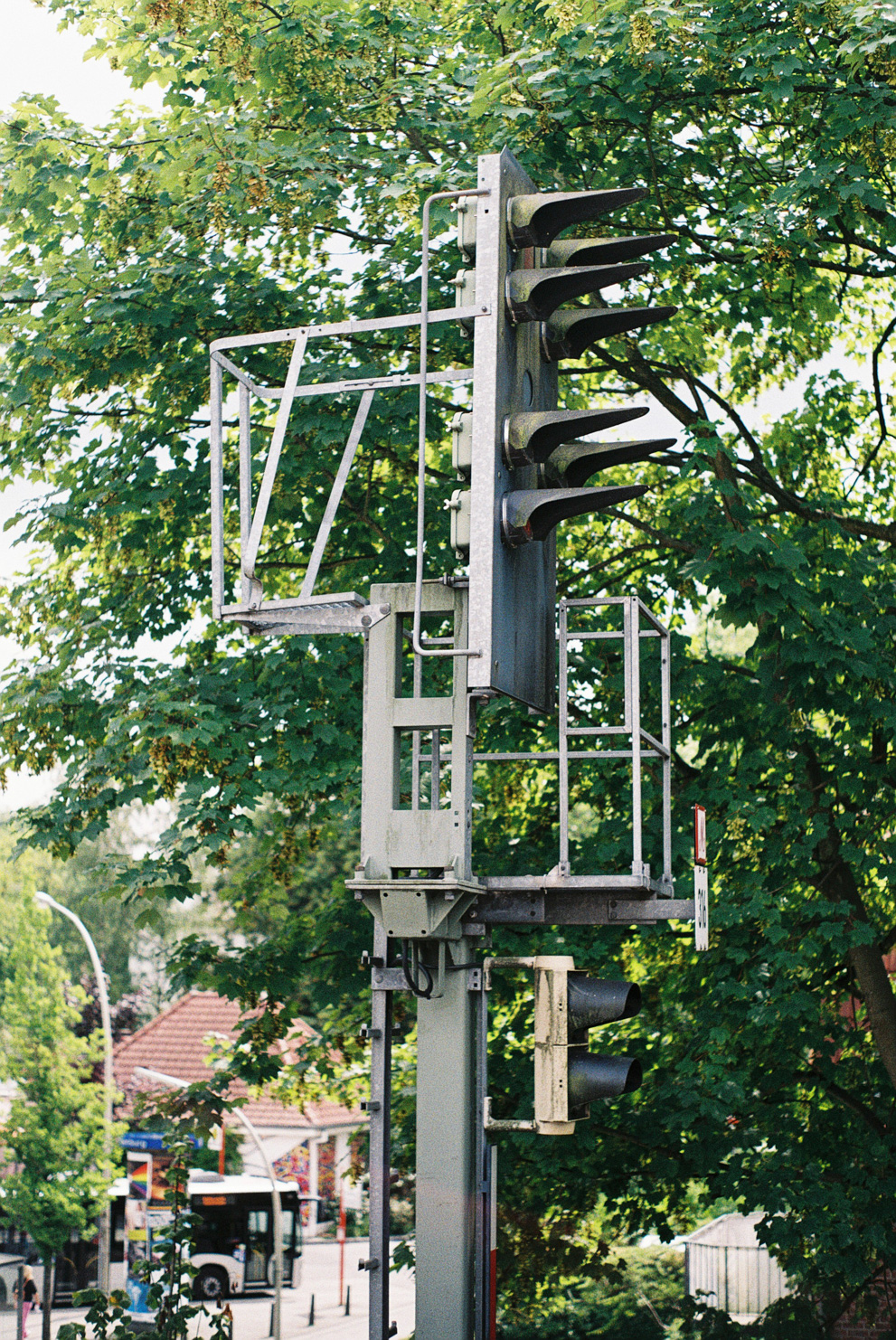 The signal lights of a tram with a tree in the background and a busstop in the lower part of the image. Shot on Fujifilm Fujicolor C200.